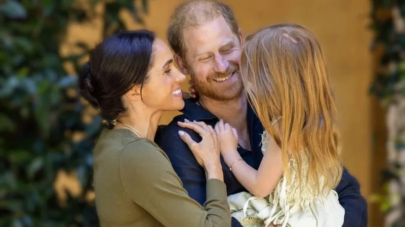 Harry and Meghan Share New Photos as Lilibet Turns Five Lilibet Celebrates Her Fifth Birthday Prince Harry and Meghan Markle marked their daughter Lilibet’s fifth birthday with new family photos. Meghan described her as their “dream girl” while sharing a warm message on social media. The couple continues to share occasional personal moments of their children, giving the public a glimpse into their family life. New Family Photos Shared The first photo shows Harry and Meghan smiling together while holding Lilibet in a close family embrace. The second image captures Lilibet outdoors in a garden. She appears relaxed and curious as she gently touches a flower. These images highlight a calm and private family setting focused on nature and togetherness. Meghan’s Birthday Message on Instagram Meghan posted the photos on Instagram and wrote, “Our dream girl. Happy 5th birthday, Lili.” She has previously shared similar moments of Lilibet, including a playful photo where she referred to her as “Mama’s little helper.” Family Life and Public Updates Lilibet is the couple’s second child and younger sister to Archie by two years. The Sussex family has gradually shared updates about their life outside royal duties. Recently, they celebrated their eighth wedding anniversary by sharing personal photographs from their wedding day. Netflix Projects and Archewell Work The couple’s production company, Archewell, is developing a feature film for Netflix. The project is based on a true story involving British troops during the Afghanistan conflict and adapts the book No Way Out by Major Adam Jowett. Their relationship with Netflix has shifted in recent years, moving from a full contract to a first look agreement, where Netflix gets the first option to review new projects. Recent Public Engagements Earlier this year, Harry and Meghan visited Australia in a private capacity. Their visit focused on Indigenous culture, sport, and community causes, along with a stop at the Australian War Memorial.