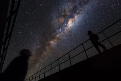 Atacama Desert’s Hidden Residencia: A Secret Base for Astronomers A building hidden in plain sight Deep in Chile’s Atacama Desert, a strange structure hides in the rocky landscape. From outside, the Residencia is almost invisible. Its entrance sits behind a plain door at the bottom of a ramp, blending into the dry terrain so well that most people walk past without noticing it. The surrounding land feels harsh and empty, with only rocky plains, distant mountains, and the occasional bird cutting through the dry sky. A sudden green world inside Stepping inside changes everything. The dry desert disappears, replaced by a cool, humid environment filled with life. Plants and trees grow in a central indoor garden, creating a green oasis in the middle of one of the driest places on Earth. At the heart of the space sits a bright blue swimming pool under a large dome. The air feels moist on the skin, a sharp contrast to the desert outside. A place that looks like a movie set The design of the Residencia gives it a cinematic feel. Its hidden corridors, open terraces, and unusual layout once attracted filmmakers. It even served as a filming location for a major spy movie finale, where dramatic scenes and explosions were shot across the building. Despite that dramatic past, the structure was not built for films. It was designed for science. Home for scientists and engineers Today, the Residencia serves as a private residence for astronomers and engineers. It cannot be booked by the public. More than one hundred rooms are reserved for staff working at nearby observatories. Most residents are involved with facilities like the Very Large Telescope on Cerro Paranal, only a short distance away. They live here while conducting research in one of the most extreme environments on the planet. Built for extreme conditions The European Southern Observatory operates the Residencia. The goal is simple: support scientific work in a remote desert where conditions are tough but the skies are perfect for astronomy. The design allows scientists to rest, recover, and continue their work without leaving the harsh environment that makes their research possible. A desert base like no other The Residencia sits between two worlds. Outside, there is silence, heat, and dry land. Inside, there is water, greenery, and calm. It feels more like a luxury retreat than a scientific base, yet its purpose is deeply practical. For the people working there, it becomes a temporary home while they study the universe from one of the clearest skies on Earth.
