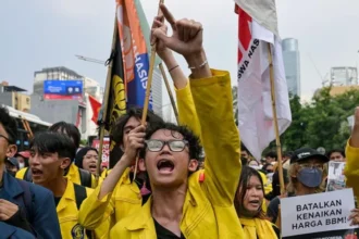 Student Protests Erupt in Jakarta Hundreds of university students gathered in Indonesia’s capital on Friday. They protested against government policies they believe are hurting the economy. Many warned that continued wasteful spending could push the country toward financial trouble. The demonstrations took place amid growing public frustration over economic management and rising living costs. Concerns Over Government Spending and Free Meals Program Protesters urged President Prabowo Subianto to cut what they called unnecessary state spending. They also demanded the cancellation of a major free meals program. Students said the program has faced serious problems, including food safety incidents and corruption concerns. They argued that public funds should be used more carefully. The program remains a key part of the president’s agenda and was central during his election campaign. Government officials say it aims to reduce child malnutrition and improve education outcomes. Fuel Price Increase Sparks Public Anger Students also opposed recent fuel price increases introduced by state energy authorities. Prices for widely used fuel types rose significantly, increasing pressure on household budgets. Many protesters said rising fuel costs are making daily life more difficult, especially for middle income families. A student voice at the protest said living costs are rising while wages remain under pressure, adding to public frustration. Clashes at Key Jakarta Landmark Tensions rose as students attempted to march toward a central landmark in Jakarta. Police formed barricades to block their path. Some demonstrators pushed against the barriers, and objects were thrown during the confrontation. Police used shields to control the crowd. No confirmed reports of serious injuries appeared at the time. Social media users shared updates under a slogan that expressed fears about the country’s economic direction. Rising Economic Pressure and Public Debate The protests come during a period of currency weakness and wider economic concern. The local currency has recently dropped to new lows, adding to financial anxiety among citizens. Public debate has grown around government priorities, especially large scale social programs versus economic stability. Critics argue that spending decisions need tighter control. Officials continue to defend current policies, saying they are designed for long term national development.