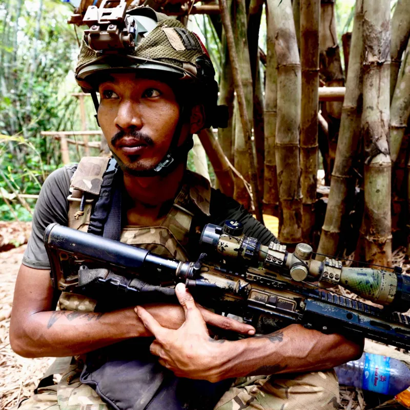 Myanmar Civil War: Forced Conscription Shifts Battlefield Balance Conscription drives civilians into conflict In Myanmar, several young men who never intended to join any armed struggle have ended up in the middle of the civil war. They describe being taken by the military in different situations, including while returning from work, traveling home late at night, or simply lacking proper identification. One former chef says he was detained on his way home and forced into service because he could not show ID. Another man recalls being picked up after a late-night karaoke visit. A third says he was arrested while working in the forestry sector. A fourth claims he was falsely accused after drugs were planted in his belongings, leading to his forced enlistment. Training and harsh conditions The men say they were given basic training for around four months before being sent to the front lines in Karen state. They describe strict routines, little rest, and heavy workloads placed mainly on conscripts rather than regular troops. They also say they were sent into active conflict quickly and had very limited time to adjust or recover. Life in the camps, they explain, was physically exhausting and tightly controlled. Escape and capture by rebel forces During a brief moment of movement away from camp, the group decided to escape. They were later found and detained by members of a local resistance group. Since then, they say they have been treated more fairly and with respect. They describe the experience as being treated like comrades rather than outsiders. They also say returning home is too dangerous. They fear being tracked or arrested again, so plans are being made to move them toward the border with Thailand for safety. Wider impact on the conflict Forced recruitment has become a key factor in changing the balance of the conflict. The military, which took control in 2021 after removing the elected government and detaining its leader Aung San Suu Kyi, has expanded conscription to strengthen its ranks. The civil war has caused widespread destruction, killing thousands and displacing millions across the country. After earlier advances by resistance groups and ethnic alliances, many of those gains have now been pushed back in several regions. The situation continues to shift, with fighting still active across multiple fronts.