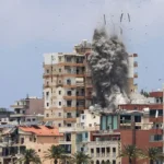Situation in Tyre, Lebanon Israeli forces launched air and artillery strikes across southern Lebanon, including the coastal city of Tyre. One strike hit a residential building close to the seafront area. The attacks came even after Iran warned Israel to stop its operations in Lebanon. Casualties and Damage Health officials in Lebanon reported that at least eight people were killed in Tyre. Other reports from Lebanese media said total deaths across southern areas reached at least thirteen on Tuesday. A drone strike near Kfar Roummane also killed two people close to Nabatieh. Evacuation Orders in the City The Israeli military ordered residents in Tyre and nearby areas to leave immediately. People were told to move beyond the Zahrani River, about 30 kilometers to the north. For the first time, the evacuation warning also included the Christian quarter of the city. Authorities said armed groups linked to Hezbollah were active in the area. Roads heading out of the city became crowded. Many families left quickly with their belongings tied to cars. Voices from Residents Residents described fear and confusion as they moved away from their homes. Some questioned the strikes and evacuation orders. One man traveling to Beirut asked what wrong they had done and why civilians were being forced to leave. Another resident heading toward Sidon said he did not believe the claims about armed activity in his area and called the situation unfair. Rising Regional Tensions The situation follows a temporary pause in hostilities between Israel and Iran after recent exchanges of strikes. Earlier attacks on Beirut targeting Iran linked groups triggered renewed fighting between the sides. Iran warned that further strikes on Lebanon could lead to retaliation. Israel said it would continue its campaign against Hezbollah despite the warnings. The wider conflict is also affecting diplomatic efforts involving the United States and President Donald Trump, who has been linked to attempts to reduce tensions in the region.