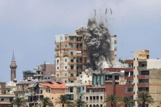 Situation in Tyre, Lebanon Israeli forces launched air and artillery strikes across southern Lebanon, including the coastal city of Tyre. One strike hit a residential building close to the seafront area. The attacks came even after Iran warned Israel to stop its operations in Lebanon. Casualties and Damage Health officials in Lebanon reported that at least eight people were killed in Tyre. Other reports from Lebanese media said total deaths across southern areas reached at least thirteen on Tuesday. A drone strike near Kfar Roummane also killed two people close to Nabatieh. Evacuation Orders in the City The Israeli military ordered residents in Tyre and nearby areas to leave immediately. People were told to move beyond the Zahrani River, about 30 kilometers to the north. For the first time, the evacuation warning also included the Christian quarter of the city. Authorities said armed groups linked to Hezbollah were active in the area. Roads heading out of the city became crowded. Many families left quickly with their belongings tied to cars. Voices from Residents Residents described fear and confusion as they moved away from their homes. Some questioned the strikes and evacuation orders. One man traveling to Beirut asked what wrong they had done and why civilians were being forced to leave. Another resident heading toward Sidon said he did not believe the claims about armed activity in his area and called the situation unfair. Rising Regional Tensions The situation follows a temporary pause in hostilities between Israel and Iran after recent exchanges of strikes. Earlier attacks on Beirut targeting Iran linked groups triggered renewed fighting between the sides. Iran warned that further strikes on Lebanon could lead to retaliation. Israel said it would continue its campaign against Hezbollah despite the warnings. The wider conflict is also affecting diplomatic efforts involving the United States and President Donald Trump, who has been linked to attempts to reduce tensions in the region.