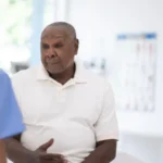 UK Expands Prostate Cancer Screening Trial for Black Men Major step in targeted prostate cancer checks The UK government has expanded a prostate cancer screening trial to include tens of thousands of black men aged 45 to 74. These men will be invited for testing to help improve early detection methods for the disease. Health officials say the aim is to find better ways of identifying prostate cancer earlier, especially in high risk groups. Black men face a much higher risk, with studies showing their lifetime chance of developing prostate cancer is about one in four. Why black men are being prioritised Prostate cancer remains the most common cancer among men in the UK. Around 64,000 men receive a diagnosis each year, and about 12,000 die from the disease. Medical data shows black men face double the risk compared to other groups. Because of this, researchers are focusing on targeted screening to close the gap in outcomes and improve survival rates. What the screening trial includes The government has committed £18 million to support the Transform trial. The study will test whether combining different methods improves accuracy. Participants may receive: PSA blood tests to detect prostate specific antigen levels Genetic testing to identify higher risk variants Faster MRI scans for more detailed imaging Researchers hope this combined approach will reduce missed cases and improve early diagnosis. Debate over routine screening Health experts continue to debate routine screening for all men. The UK National Screening Committee recently advised against regular PSA testing for most men without symptoms. They argue that PSA screening can lead to unnecessary treatment. Some prostate cancers grow slowly and may never cause harm. However, treatment can still lead to serious side effects such as bladder control problems and erectile dysfunction. For now, men are still encouraged to speak with a doctor if they notice symptoms like difficulty urinating. A step toward better future screening Officials believe the expanded trial will help shape a more accurate national screening system in the future. Health leaders say the focus is now on improving precision rather than broad testing. A health spokesperson said the programme is designed to focus on those most at risk and strengthen research to close evidence gaps. Readability and SEO Impro