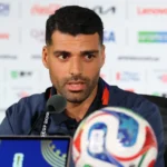 # Iran World Cup Political Tensions Overshadow Team's Tournament Journey ## Political Challenges Cast Shadow Over Iran's World Cup Campaign Iran has entered the FIFA World Cup under unusual circumstances, with political tensions affecting the team's preparations and overall experience. Although a recent agreement helped reduce hostilities between Iran and the United States, the atmosphere surrounding the tournament remains sensitive. Iranian striker Mehdi Taremi admitted that the ongoing situation has taken some of the excitement away from football's biggest event. According to him, the pressure began even before the team arrived in the United States. He explained that the squad felt the tension from the start of its World Cup journey. As a result, the players faced additional challenges while preparing for the competition. ## Visa Issues and Relocation Disrupt Preparations Months of uncertainty forced Iran to change its World Cup base camp plans. Initially, the team intended to stay in Tucson, Arizona. However, concerns regarding visas, security, and the political climate led officials to relocate the camp to Tijuana, Mexico. The move created logistical difficulties and reduced the team's preparation time before the tournament. Iran's head coach, Amir Ghalenoei, acknowledged that these challenges affected the squad's focus. He emphasized that football should unite people from different backgrounds and cultures. Despite the distractions, he has encouraged his players to remain focused on tactics and performance. The coach also pointed out that the team arrived later than expected, leaving less time to adapt to local conditions. Nevertheless, he expressed confidence in his players' commitment and determination. ## Los Angeles Becomes Center of Attention Iran will begin its World Cup campaign against New Zealand at SoFi Stadium in Los Angeles. The city is home to one of the largest Iranian communities outside Iran and is often referred to as "Tehrangeles." Many Iranian Americans are expected to attend the match. However, not everyone will be there solely to support the team. Several groups plan to hold demonstrations outside the stadium. The protests stem from concerns surrounding political issues and restrictions on displaying the historic Lion and Sun flag, a symbol that holds significant meaning for many Iranians living abroad. ## Diaspora Voices Concerns Ahead of Match Members of the Iranian diaspora have expressed frustration over the ban on the Lion and Sun flag during the tournament. Activists argue that the symbol represents cultural identity and historical heritage rather than political affiliation. Many expatriate Iranians continue to criticize the Iranian government and believe sports should remain separate from politics. Some activists worry that athletes often become linked to political debates beyond their control. Despite these disagreements, many members of the Iranian community still plan to attend the match. Their presence highlights the strong connection between football, national identity, and global politics. ## Football Remains the Main Focus While political discussions continue around the tournament, Iran's players remain focused on their performances on the field. The team hopes to overcome external challenges and make a strong impression during the World Cup. For the players, the primary goal remains simple: represent their country with pride and compete at the highest level of international football. As Iran prepares for its opening match against New Zealand, fans around the world will watch closely to see whether the team can rise above the off-field distractions and focus on success where it matters most, on the pitch.