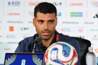 # Iran World Cup Political Tensions Overshadow Team's Tournament Journey ## Political Challenges Cast Shadow Over Iran's World Cup Campaign Iran has entered the FIFA World Cup under unusual circumstances, with political tensions affecting the team's preparations and overall experience. Although a recent agreement helped reduce hostilities between Iran and the United States, the atmosphere surrounding the tournament remains sensitive. Iranian striker Mehdi Taremi admitted that the ongoing situation has taken some of the excitement away from football's biggest event. According to him, the pressure began even before the team arrived in the United States. He explained that the squad felt the tension from the start of its World Cup journey. As a result, the players faced additional challenges while preparing for the competition. ## Visa Issues and Relocation Disrupt Preparations Months of uncertainty forced Iran to change its World Cup base camp plans. Initially, the team intended to stay in Tucson, Arizona. However, concerns regarding visas, security, and the political climate led officials to relocate the camp to Tijuana, Mexico. The move created logistical difficulties and reduced the team's preparation time before the tournament. Iran's head coach, Amir Ghalenoei, acknowledged that these challenges affected the squad's focus. He emphasized that football should unite people from different backgrounds and cultures. Despite the distractions, he has encouraged his players to remain focused on tactics and performance. The coach also pointed out that the team arrived later than expected, leaving less time to adapt to local conditions. Nevertheless, he expressed confidence in his players' commitment and determination. ## Los Angeles Becomes Center of Attention Iran will begin its World Cup campaign against New Zealand at SoFi Stadium in Los Angeles. The city is home to one of the largest Iranian communities outside Iran and is often referred to as "Tehrangeles." Many Iranian Americans are expected to attend the match. However, not everyone will be there solely to support the team. Several groups plan to hold demonstrations outside the stadium. The protests stem from concerns surrounding political issues and restrictions on displaying the historic Lion and Sun flag, a symbol that holds significant meaning for many Iranians living abroad. ## Diaspora Voices Concerns Ahead of Match Members of the Iranian diaspora have expressed frustration over the ban on the Lion and Sun flag during the tournament. Activists argue that the symbol represents cultural identity and historical heritage rather than political affiliation. Many expatriate Iranians continue to criticize the Iranian government and believe sports should remain separate from politics. Some activists worry that athletes often become linked to political debates beyond their control. Despite these disagreements, many members of the Iranian community still plan to attend the match. Their presence highlights the strong connection between football, national identity, and global politics. ## Football Remains the Main Focus While political discussions continue around the tournament, Iran's players remain focused on their performances on the field. The team hopes to overcome external challenges and make a strong impression during the World Cup. For the players, the primary goal remains simple: represent their country with pride and compete at the highest level of international football. As Iran prepares for its opening match against New Zealand, fans around the world will watch closely to see whether the team can rise above the off-field distractions and focus on success where it matters most, on the pitch.