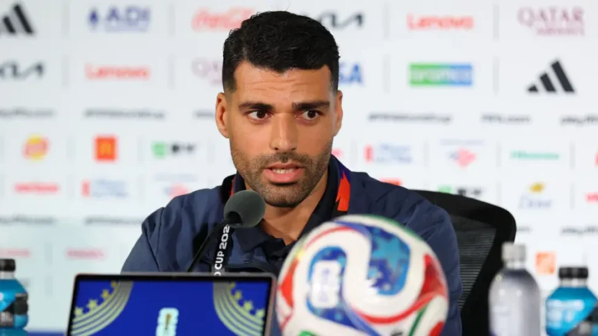 # Iran World Cup Political Tensions Overshadow Team's Tournament Journey ## Political Challenges Cast Shadow Over Iran's World Cup Campaign Iran has entered the FIFA World Cup under unusual circumstances, with political tensions affecting the team's preparations and overall experience. Although a recent agreement helped reduce hostilities between Iran and the United States, the atmosphere surrounding the tournament remains sensitive. Iranian striker Mehdi Taremi admitted that the ongoing situation has taken some of the excitement away from football's biggest event. According to him, the pressure began even before the team arrived in the United States. He explained that the squad felt the tension from the start of its World Cup journey. As a result, the players faced additional challenges while preparing for the competition. ## Visa Issues and Relocation Disrupt Preparations Months of uncertainty forced Iran to change its World Cup base camp plans. Initially, the team intended to stay in Tucson, Arizona. However, concerns regarding visas, security, and the political climate led officials to relocate the camp to Tijuana, Mexico. The move created logistical difficulties and reduced the team's preparation time before the tournament. Iran's head coach, Amir Ghalenoei, acknowledged that these challenges affected the squad's focus. He emphasized that football should unite people from different backgrounds and cultures. Despite the distractions, he has encouraged his players to remain focused on tactics and performance. The coach also pointed out that the team arrived later than expected, leaving less time to adapt to local conditions. Nevertheless, he expressed confidence in his players' commitment and determination. ## Los Angeles Becomes Center of Attention Iran will begin its World Cup campaign against New Zealand at SoFi Stadium in Los Angeles. The city is home to one of the largest Iranian communities outside Iran and is often referred to as "Tehrangeles." Many Iranian Americans are expected to attend the match. However, not everyone will be there solely to support the team. Several groups plan to hold demonstrations outside the stadium. The protests stem from concerns surrounding political issues and restrictions on displaying the historic Lion and Sun flag, a symbol that holds significant meaning for many Iranians living abroad. ## Diaspora Voices Concerns Ahead of Match Members of the Iranian diaspora have expressed frustration over the ban on the Lion and Sun flag during the tournament. Activists argue that the symbol represents cultural identity and historical heritage rather than political affiliation. Many expatriate Iranians continue to criticize the Iranian government and believe sports should remain separate from politics. Some activists worry that athletes often become linked to political debates beyond their control. Despite these disagreements, many members of the Iranian community still plan to attend the match. Their presence highlights the strong connection between football, national identity, and global politics. ## Football Remains the Main Focus While political discussions continue around the tournament, Iran's players remain focused on their performances on the field. The team hopes to overcome external challenges and make a strong impression during the World Cup. For the players, the primary goal remains simple: represent their country with pride and compete at the highest level of international football. As Iran prepares for its opening match against New Zealand, fans around the world will watch closely to see whether the team can rise above the off-field distractions and focus on success where it matters most, on the pitch.