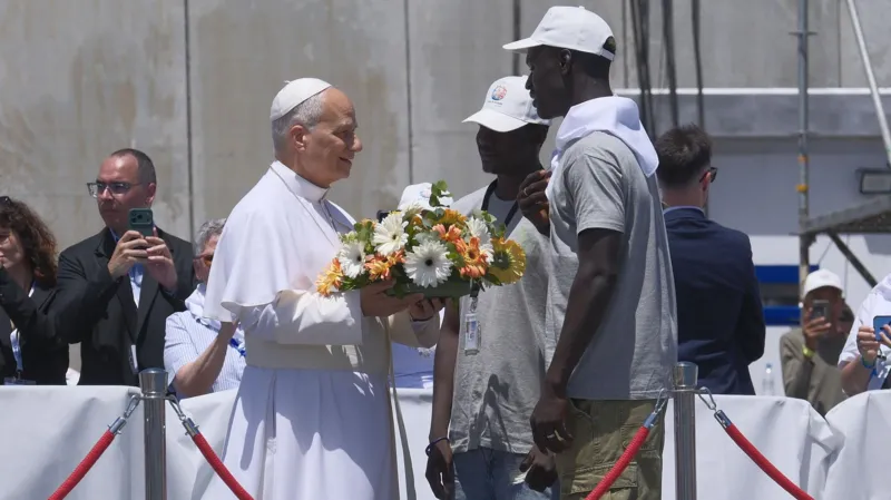 Pope Leo XIV Visits Canary Islands to Highlight Migrant Sea Journeys Pope Meets Migrants in Gran Canaria Pope Leo XIV started his visit to the Canary Islands by meeting migrants in Gran Canaria. He listened to personal stories of people who crossed the Atlantic in unsafe conditions in search of a better life. He told them they are not just numbers or records but real human beings with dignity. He also said he bows in respect to their struggles and survival. Call for Safe Migration Routes During his visit, the Pope spoke about the need for legal and safe pathways for migration. He urged European leaders and societies not to become numb to deaths at sea. He warned that the oceans should not become silent graves for people trying to reach safety. He called on conscience and responsibility in handling migration policies. Tribute at Sea for Lives Lost At the port of Arguineguín in southern Gran Canaria, the Pope paid tribute to migrants who died during their journeys. He placed a wreath of flowers into the sea and prayed in silence. His message focused on remembering those who disappeared without any trace during Atlantic crossings. Dangerous Journey Across the Atlantic Data from the UNHCR shows that arrivals to Spain by sea have decreased this year. This decline is partly linked to stronger patrols along West African waters supported by European funding. Even with fewer arrivals, many migrants continue to attempt the journey. Many still lose their lives at sea. Survivor Story from The Gambia One survivor, Bakary Jaiju from The Gambia, shared his experience of crossing the Atlantic at age 19. He traveled in a wooden boat with around 160 people including women and children. He described a journey lasting seven days with very limited food and water. Fear was constant as passengers risked falling into the sea. Jaiju said he left his family behind because he wanted to improve their living conditions, even if it meant risking his life. Rescue and Life After Arrival When the boat ran out of fuel near El Hierro, Spanish rescue teams found and saved the passengers. After arrival, Jaiju spent three difficult months in a migrant camp. Later, he joined a support program in Tenerife to learn Spanish and work toward legal residence. A local parish priest known as Padre Pepe supports migrants through community programs that help them adjust and rebuild their lives.