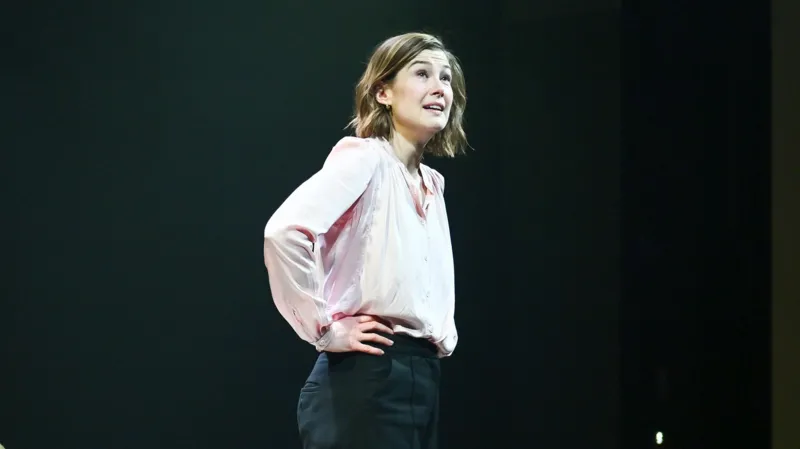 Rosamund Pike Addresses Theatre Etiquette After Audience Member Texting Incident in West End Show Actor pauses curtain call moment to speak about distraction during emotional scene Rosamund Pike interrupted the usual end-of-show atmosphere at London’s Wyndham’s Theatre after noticing an audience member texting during a powerful moment in her West End performance of Inter Alia. The incident happened on Saturday during the closing stages of the play. Pike, known for Gone Girl, Saltburn, Pride & Prejudice, and Die Another Day, returned to the stage alone after the performance. Instead of a standard curtain call announcement, she spoke directly to the audience about theatre behaviour and focus during live acting. Emotional moment prompts onstage message During her brief speech, Pike explained that she and the cast could see audience behaviour and feel its impact during performance. She said it becomes difficult to stay fully immersed when attention is pulled away in key emotional scenes. She avoided directly identifying the person involved but made it clear that texting had been noticed in a crucial moment of the play. Her tone mixed frustration with understanding, as she suggested the message might have been urgent and even joked that the person could be a doctor dealing with an emergency. Call for respect in live theatre spaces Pike stressed that live theatre depends on shared attention between performers and audience. She reminded attendees that the story being told on stage requires focus and emotional engagement from both sides. Her comments were not aggressive, but firm, as she encouraged people to treat theatre as a space that deserves full presence. She also asked the audience not to record her remarks. Audience reaction and response The moment drew gasps from the crowd, followed by applause after she finished speaking. Some audience members later described the atmosphere as uncomfortable at first, then supportive of Pike’s message. One attendee said they initially expected a routine announcement but were surprised by her direct address about the texting incident. About Inter Alia and Pike’s role Inter Alia is a courtroom focused drama written by Suzie Miller, exploring themes of justice, family pressure, and sexual assault within the legal system. Pike plays Jessica Parks, a Crown Court judge balancing intense professional and personal challenges. Earlier in the year, Pike received recognition for her performance, winning a major theatre award for the role.