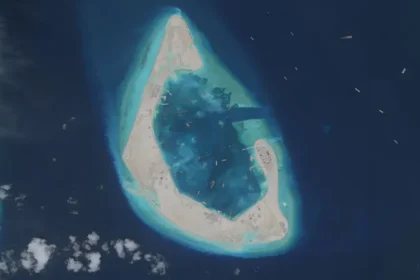 A rapidly changing landscape in the South China Sea Antelope Reef, located in the north west of the South China Sea, has changed beyond recognition. Until recently, it was mostly underwater and barely visible above the waves. Now it has become a newly formed island stretching around six square kilometres, built in just half a year. Satellite images show a bright white sand formation shaped like a crescent. Small structures have already appeared on one side. Inside the lagoon, a large number of vessels are operating, believed to be powerful dredging ships used to reshape the seabed. Massive dredging operations reshape reefs China operates one of the largest dredging fleets in the world. Some of these ships can move around 6,000 cubic metres of sand per hour. That is enough material to fill two Olympic sized swimming pools in a single hour. Millions of tonnes of sand have been extracted from the seabed to create solid ground. The speed of this transformation is among the fastest recorded for such projects. Regional powers expand their presence China is not acting alone in reshaping reefs in the region. Vietnam has also begun strengthening and expanding reefs under its control in response to earlier Chinese projects. The Philippines and other claimants are also carrying out smaller scale construction activities. These developments reflect growing competition over territory in the South China Sea. Disputed waters and rising tensions The South China Sea is claimed by China, Taiwan, Vietnam, the Philippines, Malaysia, and Brunei. Most of the reefs involved were once submerged and had no permanent population. China took control of the Paracel Islands in 1974 after a conflict with South Vietnamese forces. Since then, it has expanded its presence significantly across the region. In recent years, China has built artificial islands on reefs such as Mischief, Fiery Cross, and Subi in the Spratly Islands. These islands now support airstrips and military facilities. Military concerns and strategic messaging China’s coastguard and maritime militia regularly patrol within its claimed nine dash line boundary. This has increased tensions with neighbouring countries, especially the Philippines, where several confrontations have occurred at sea. The shape and construction style of Antelope Reef suggests the possibility of future military use, including a potential runway. However, China already operates nearby airstrips on Woody Island and Hainan Island. Analysts suggest the latest expansion may be less about immediate military need and more about signalling control over the region