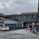 Two Men Arrested in Nottingham Mortuary Investigation Linked to Maternity Failures Police Action in Operation Perth Two men, aged 55 and 59, have been arrested in Nottingham over concerns linked to practices in a hospital mortuary service. They are suspected of misconduct in a public office. Police confirmed the arrests took place on Monday. Nottinghamshire Police are running the inquiry under Operation Perth, which started in 2023 after serious maternity care failings were identified at Nottingham University Hospitals NHS Trust. Background of the Maternity Investigation The investigation is tied to wider concerns that involve hundreds of cases where babies died or were harmed. The issues are part of a major maternity review in the NHS, which is one of the largest of its kind. The review is led by independent senior midwife Donna Ockenden. It covers around 2,500 cases and began in September 2022 after repeated allegations of poor care affecting mothers and newborns. Mortuary Service Under Scrutiny Nottingham University Hospitals NHS Trust runs mortuary services at both Queen’s Medical Centre and Nottingham City Hospital. These services operate under a licence from the Human Tissue Authority. Police say Operation Perth identified breaches of regulations under the Human Tissue Act. These breaches relate to how mortuary services were managed and run. Support for Affected Families Deputy Chief Constable Rob Griffin said the investigation may be distressing for families already involved in the case. He confirmed that families directly affected have been contacted. He added that more families will be informed as investigators identify further cases. Support services are also available through the Operation Perth information channels. Hospital Response Manjeet Shehmar, medical director at Nottingham University Hospitals NHS Trust, said the trust is aware of the arrests. He said the organisation is taking the matter seriously and will fully cooperate with the investigation.