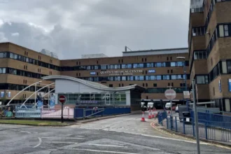 Two Men Arrested in Nottingham Mortuary Investigation Linked to Maternity Failures Police Action in Operation Perth Two men, aged 55 and 59, have been arrested in Nottingham over concerns linked to practices in a hospital mortuary service. They are suspected of misconduct in a public office. Police confirmed the arrests took place on Monday. Nottinghamshire Police are running the inquiry under Operation Perth, which started in 2023 after serious maternity care failings were identified at Nottingham University Hospitals NHS Trust. Background of the Maternity Investigation The investigation is tied to wider concerns that involve hundreds of cases where babies died or were harmed. The issues are part of a major maternity review in the NHS, which is one of the largest of its kind. The review is led by independent senior midwife Donna Ockenden. It covers around 2,500 cases and began in September 2022 after repeated allegations of poor care affecting mothers and newborns. Mortuary Service Under Scrutiny Nottingham University Hospitals NHS Trust runs mortuary services at both Queen’s Medical Centre and Nottingham City Hospital. These services operate under a licence from the Human Tissue Authority. Police say Operation Perth identified breaches of regulations under the Human Tissue Act. These breaches relate to how mortuary services were managed and run. Support for Affected Families Deputy Chief Constable Rob Griffin said the investigation may be distressing for families already involved in the case. He confirmed that families directly affected have been contacted. He added that more families will be informed as investigators identify further cases. Support services are also available through the Operation Perth information channels. Hospital Response Manjeet Shehmar, medical director at Nottingham University Hospitals NHS Trust, said the trust is aware of the arrests. He said the organisation is taking the matter seriously and will fully cooperate with the investigation.