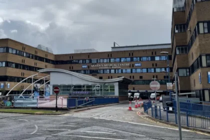 Two Men Arrested in Nottingham Mortuary Investigation Linked to Maternity Failures Police Action in Operation Perth Two men, aged 55 and 59, have been arrested in Nottingham over concerns linked to practices in a hospital mortuary service. They are suspected of misconduct in a public office. Police confirmed the arrests took place on Monday. Nottinghamshire Police are running the inquiry under Operation Perth, which started in 2023 after serious maternity care failings were identified at Nottingham University Hospitals NHS Trust. Background of the Maternity Investigation The investigation is tied to wider concerns that involve hundreds of cases where babies died or were harmed. The issues are part of a major maternity review in the NHS, which is one of the largest of its kind. The review is led by independent senior midwife Donna Ockenden. It covers around 2,500 cases and began in September 2022 after repeated allegations of poor care affecting mothers and newborns. Mortuary Service Under Scrutiny Nottingham University Hospitals NHS Trust runs mortuary services at both Queen’s Medical Centre and Nottingham City Hospital. These services operate under a licence from the Human Tissue Authority. Police say Operation Perth identified breaches of regulations under the Human Tissue Act. These breaches relate to how mortuary services were managed and run. Support for Affected Families Deputy Chief Constable Rob Griffin said the investigation may be distressing for families already involved in the case. He confirmed that families directly affected have been contacted. He added that more families will be informed as investigators identify further cases. Support services are also available through the Operation Perth information channels. Hospital Response Manjeet Shehmar, medical director at Nottingham University Hospitals NHS Trust, said the trust is aware of the arrests. He said the organisation is taking the matter seriously and will fully cooperate with the investigation.