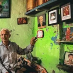 We Don’t Look at the Sky Anymore: Families Living with the Ahmedabad Air Crash Tragedy Introduction Ahmedabad is still living with the memory of a devastating air crash that killed 260 people. Most were passengers on the plane, but 19 people on the ground also lost their lives when the aircraft struck the BJ Medical College hostel area near the airport. One year later, grief has not faded for families who live nearby. Lives Changed in an Instant Prahlod Thakur lost his wife, Sarlaben, and his granddaughter, Aadhya. They were inside the hostel complex when the crash happened. Their photos still hang on the walls of his home. He sees them every morning. The loss remains heavy, and he often feels overwhelmed when he looks at their pictures. A Site That Never Healed The hostel building still shows clear damage. Upper floors remain open to the sky. Concrete is broken and scattered. Stairs are dark with burn marks. Personal items are still buried in dust and debris. The building has not returned to normal use. Plans exist to demolish it and rebuild, but no full cleanup has taken place yet. Daily Life Around the Ruins Students continue their studies nearby. They walk past the damaged building every day. Air traffic still passes overhead frequently. Before the crash, the sound of planes felt normal. Now it brings back painful memories for many residents and students. Grief That Does Not Fade For families like Thakur’s, healing feels out of reach. The sound of a passing aircraft brings back the same shock they felt during the disaster. Many say they avoid looking at the sky. The tragedy has changed how they experience everyday life. Future Plans and Uncertain Closure Authorities have approved demolition of the damaged hostel complex. A new building is planned for the site. However, the delay in removal of the wreckage has kept the emotional wound open for many families and students.