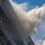 Antwerp Apartment Fire Kills Six, Dozens Injured After Massive Blaze Tragic Fire Breaks Out in Antwerp Residential Building At least six people lost their lives and several others suffered injuries after a devastating fire swept through a 10 storey apartment building in Antwerp, Belgium, on Wednesday morning. Emergency services rushed to the scene after the fire started shortly before 10:00 local time in the Linkeroever district. The blaze produced thick black smoke that quickly spread through the building, forcing residents to escape under dangerous conditions. Firefighters launched a large scale rescue operation as smoke filled multiple floors. Hundreds of Residents Affected Authorities confirmed that more than 200 people live in the apartment complex. Rescue teams evacuated around 80 flats to protect residents from the rapidly spreading smoke. Officials later said that a technical problem on the ground floor likely caused the fire. Investigators continue to examine the exact circumstances surrounding the incident. Emergency crews remained at the site for several hours to secure the building and search every apartment for anyone who might still be trapped. Dramatic Escape Captured on Video Several residents faced terrifying moments while trying to escape. One widely shared video showed a man climbing from his balcony into a neighboring apartment through a window to avoid the heavy smoke. Another resident explained that smoke blocked every possible exit from his apartment. He and his family stayed inside, moved onto their balcony, and waited for firefighters. Rescue crews arrived with a ladder within minutes and safely brought them down. Firefighters Face Difficult Conditions Firefighters worked under extremely challenging conditions because thick smoke reduced visibility throughout the building. The smoke spread much faster than expected, making evacuations more difficult. Rescue teams searched each apartment one by one to ensure that no residents remained inside. Authorities said the fire was nearly under control by Wednesday afternoon, although emergency crews continued inspecting the building for safety. Families Escape, But Pets Could Not Be Saved One resident said his parents in law, including former Antwerp mayor Bob Cools, escaped safely and received medical treatment at a nearby hospital. He also shared that despite every effort by rescuers, the family's pet cat could not be saved. Belgian Leaders Express Condolences Belgian Prime Minister Bart De Wever expressed sympathy for the victims, injured residents, and everyone affected by the tragedy. He described the incident as a heartbreaking event for the Linkeroever community. Lawmakers in the Flemish Parliament also honored the victims by observing a minute of silence before beginning their parliamentary session. Investigation Continues Authorities continue investigating the cause of the fire while engineers assess the building's structural safety. Officials are also providing support to displaced families who cannot yet return to their homes. The tragic incident has raised fresh concerns about fire safety in residential buildings and the importance of emergency evacuation procedures. Local authorities are expected to release additional information as the investigation progresses.