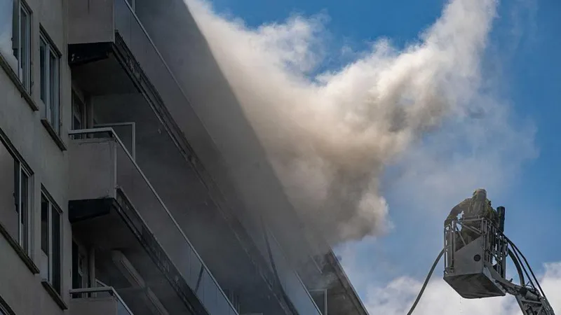 Antwerp Apartment Fire Kills Six, Dozens Injured After Massive Blaze Tragic Fire Breaks Out in Antwerp Residential Building At least six people lost their lives and several others suffered injuries after a devastating fire swept through a 10 storey apartment building in Antwerp, Belgium, on Wednesday morning. Emergency services rushed to the scene after the fire started shortly before 10:00 local time in the Linkeroever district. The blaze produced thick black smoke that quickly spread through the building, forcing residents to escape under dangerous conditions. Firefighters launched a large scale rescue operation as smoke filled multiple floors. Hundreds of Residents Affected Authorities confirmed that more than 200 people live in the apartment complex. Rescue teams evacuated around 80 flats to protect residents from the rapidly spreading smoke. Officials later said that a technical problem on the ground floor likely caused the fire. Investigators continue to examine the exact circumstances surrounding the incident. Emergency crews remained at the site for several hours to secure the building and search every apartment for anyone who might still be trapped. Dramatic Escape Captured on Video Several residents faced terrifying moments while trying to escape. One widely shared video showed a man climbing from his balcony into a neighboring apartment through a window to avoid the heavy smoke. Another resident explained that smoke blocked every possible exit from his apartment. He and his family stayed inside, moved onto their balcony, and waited for firefighters. Rescue crews arrived with a ladder within minutes and safely brought them down. Firefighters Face Difficult Conditions Firefighters worked under extremely challenging conditions because thick smoke reduced visibility throughout the building. The smoke spread much faster than expected, making evacuations more difficult. Rescue teams searched each apartment one by one to ensure that no residents remained inside. Authorities said the fire was nearly under control by Wednesday afternoon, although emergency crews continued inspecting the building for safety. Families Escape, But Pets Could Not Be Saved One resident said his parents in law, including former Antwerp mayor Bob Cools, escaped safely and received medical treatment at a nearby hospital. He also shared that despite every effort by rescuers, the family's pet cat could not be saved. Belgian Leaders Express Condolences Belgian Prime Minister Bart De Wever expressed sympathy for the victims, injured residents, and everyone affected by the tragedy. He described the incident as a heartbreaking event for the Linkeroever community. Lawmakers in the Flemish Parliament also honored the victims by observing a minute of silence before beginning their parliamentary session. Investigation Continues Authorities continue investigating the cause of the fire while engineers assess the building's structural safety. Officials are also providing support to displaced families who cannot yet return to their homes. The tragic incident has raised fresh concerns about fire safety in residential buildings and the importance of emergency evacuation procedures. Local authorities are expected to release additional information as the investigation progresses.