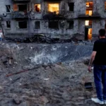 Russia Launches Largest Overnight Missile and Drone Attack on Kyiv, Killing 27 Kyiv Faces One of the Biggest Attacks Since the War Began Russia launched its largest overnight drone and missile assault on Kyiv, leaving at least 27 people dead and 91 others injured. Among the injured were two children. Officials described the attack as the biggest strike on the Ukrainian capital in terms of the number of missiles and drones used. The heavy bombardment damaged homes, public buildings, and emergency facilities across several parts of the city. Authorities ordered evacuations in affected neighborhoods while rescue teams rushed to search for survivors trapped under collapsed buildings. Residential Areas Suffer Heavy Damage One of the worst affected locations was the Darnytskyi district in southeastern Kyiv. Two missiles struck close to a residential area, causing widespread destruction. The first missile created a huge crater beside a kindergarten. The explosion damaged nearby apartment buildings and left balconies twisted and burned. Moments later, a second missile hit the end of a nine story apartment building. A large section collapsed into a pile of concrete and debris. Rescue workers continued searching through the rubble as worried families waited nearby for news of missing relatives. Many vehicles were destroyed, windows shattered, and thick layers of ash covered streets and buildings across the neighborhood. Thousands Take Shelter Underground As air raid sirens sounded across the capital, thousands of residents rushed to underground metro stations for safety. According to city officials, around 52,500 people sheltered in Kyiv's subway system during the attack. The group included about 4,500 children. Authorities said this was one of the highest numbers recorded in recent years. Survivors Share Their Experiences Residents described the terrifying moments during the overnight strikes. Svitlana, who lives next to the damaged apartment block, said she stayed in her hallway while explosions shook the area. She explained that years of living through attacks had changed how she reacted to the sound of missiles. Her family has already suffered devastating losses during the war. A previous strike killed her mother, and her son later died while serving in Ukraine's military. Another resident, Oleksiy, suffered cuts after flying glass struck him. He had stepped outside after hearing the first explosion when the second missile landed nearby. Despite his injuries, he survived the attack. Russia and Ukraine Exchange Accusations Russian officials said the overnight strikes targeted military production facilities. Moscow claimed the operation responded to recent attacks on Russian civilian infrastructure and stated that pressure on Ukraine would continue. Ukraine strongly rejected those claims. Officials argued that the missiles struck residential neighborhoods instead of military sites. They also said the attack should not be compared with Ukraine's actions because the country is defending itself against the invasion. Rescue Operations Continue Emergency crews continued clearing debris throughout the day as they searched for anyone still trapped beneath collapsed buildings. The latest assault highlights the continuing danger facing civilians in Kyiv. As rescue operations move forward, officials fear the number of casualties could rise if more victims are found under the rubble.