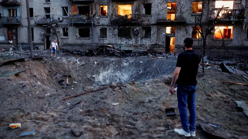 Russia Launches Largest Overnight Missile and Drone Attack on Kyiv, Killing 27 Kyiv Faces One of the Biggest Attacks Since the War Began Russia launched its largest overnight drone and missile assault on Kyiv, leaving at least 27 people dead and 91 others injured. Among the injured were two children. Officials described the attack as the biggest strike on the Ukrainian capital in terms of the number of missiles and drones used. The heavy bombardment damaged homes, public buildings, and emergency facilities across several parts of the city. Authorities ordered evacuations in affected neighborhoods while rescue teams rushed to search for survivors trapped under collapsed buildings. Residential Areas Suffer Heavy Damage One of the worst affected locations was the Darnytskyi district in southeastern Kyiv. Two missiles struck close to a residential area, causing widespread destruction. The first missile created a huge crater beside a kindergarten. The explosion damaged nearby apartment buildings and left balconies twisted and burned. Moments later, a second missile hit the end of a nine story apartment building. A large section collapsed into a pile of concrete and debris. Rescue workers continued searching through the rubble as worried families waited nearby for news of missing relatives. Many vehicles were destroyed, windows shattered, and thick layers of ash covered streets and buildings across the neighborhood. Thousands Take Shelter Underground As air raid sirens sounded across the capital, thousands of residents rushed to underground metro stations for safety. According to city officials, around 52,500 people sheltered in Kyiv's subway system during the attack. The group included about 4,500 children. Authorities said this was one of the highest numbers recorded in recent years. Survivors Share Their Experiences Residents described the terrifying moments during the overnight strikes. Svitlana, who lives next to the damaged apartment block, said she stayed in her hallway while explosions shook the area. She explained that years of living through attacks had changed how she reacted to the sound of missiles. Her family has already suffered devastating losses during the war. A previous strike killed her mother, and her son later died while serving in Ukraine's military. Another resident, Oleksiy, suffered cuts after flying glass struck him. He had stepped outside after hearing the first explosion when the second missile landed nearby. Despite his injuries, he survived the attack. Russia and Ukraine Exchange Accusations Russian officials said the overnight strikes targeted military production facilities. Moscow claimed the operation responded to recent attacks on Russian civilian infrastructure and stated that pressure on Ukraine would continue. Ukraine strongly rejected those claims. Officials argued that the missiles struck residential neighborhoods instead of military sites. They also said the attack should not be compared with Ukraine's actions because the country is defending itself against the invasion. Rescue Operations Continue Emergency crews continued clearing debris throughout the day as they searched for anyone still trapped beneath collapsed buildings. The latest assault highlights the continuing danger facing civilians in Kyiv. As rescue operations move forward, officials fear the number of casualties could rise if more victims are found under the rubble.