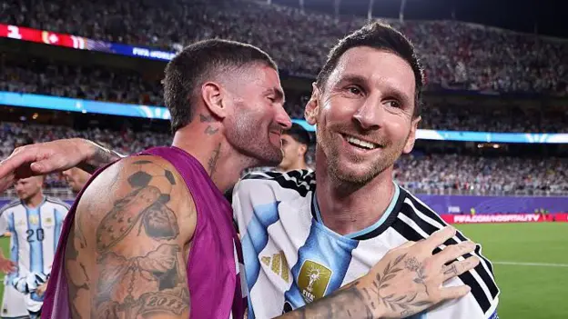 How Argentina's Team Spirit Gives Lionel Messi the Perfect World Cup Stage Messi Finds Joy and Relief in Argentina's United Squad Lionel Messi has always carried high expectations whenever he wears Argentina's shirt. During the 2026 FIFA World Cup, those emotions have become even stronger as he aims to guide his country to another historic title. After Argentina recovered from two goals down to secure a dramatic place in the World Cup quarter finals, Messi could not hold back his emotions. His tears reflected more than happiness. They showed relief after missing a penalty earlier in the match, a mistake that briefly threatened Argentina's hopes. He also continues to deal with personal concerns after learning about his father's health problems earlier in the tournament. Despite those challenges, Messi appears happier than ever within the national team setup. The strong connection between the players has created an atmosphere where he feels relaxed, trusted, and fully supported. Lionel Scaloni Builds a Team Around Togetherness Argentina manager Lionel Scaloni believes success comes from unity rather than tactics alone. While formations remain important, he places greater value on friendship and togetherness inside the squad. The players regularly spend time together away from the pitch. They share traditional mate tea, enjoy barbecues, and play the popular Argentine card game Truco. These simple activities have strengthened relationships and created a close knit dressing room. As a result, Messi has rediscovered the enjoyment of representing his country. Surrounded by teammates who understand him both as a footballer and as a person, he looks more comfortable than he has in many previous international tournaments. Rodrigo De Paul Becomes Messi's Closest Ally One of the strongest friendships inside the Argentina camp is between Messi and Rodrigo De Paul. Their relationship started during international duty after De Paul noticed Messi spending time alone following a training session. He invited the captain to share mate and play cards, beginning a friendship that has only grown stronger. Now, the two share a daily routine. Every morning, Messi visits De Paul's room for mate before other teammates arrive. The tradition has become an important part of life inside the squad. Unlike many people who treat Messi as a global superstar, De Paul treats him like any other teammate. He jokes with him, calls him "El Pequeño," and knows when to offer support or give him space. That balance has helped Messi feel comfortable throughout the tournament. Argentina Players Rally Around Their Captain The entire Argentina squad openly shows its admiration for Messi. Many players grew up watching him and credit him for inspiring their own football careers. Before matches, De Paul often walks beside Messi as the team enters the field, while the rest of the players follow closely behind. The image reflects a squad determined to protect and support its captain in every situation. The players also wear the same Adidas Messi boots as a symbol of unity. On Messi's birthday, the squad celebrated by wearing shirts featuring old photographs taken with him during different stages of his international career. These gestures highlight the respect and affection that exist within the group. Teamwork Gives Argentina Confidence Argentina's success has not depended on individual brilliance alone. The team's chemistry, trust, and shared purpose have created the ideal environment for Messi to perform at his best. As the World Cup reaches its final stages, Argentina believe their greatest strength is not only the world's greatest player but also the close bond shared by every member of the squad. That unity could prove decisive as they continue their pursuit of another world championship.