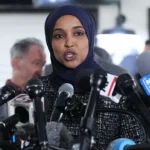 Homeland Security officer walks along a Washington, D.C., street during the October 12, 2026, investigation at Representative Ilhan Omar's residence.